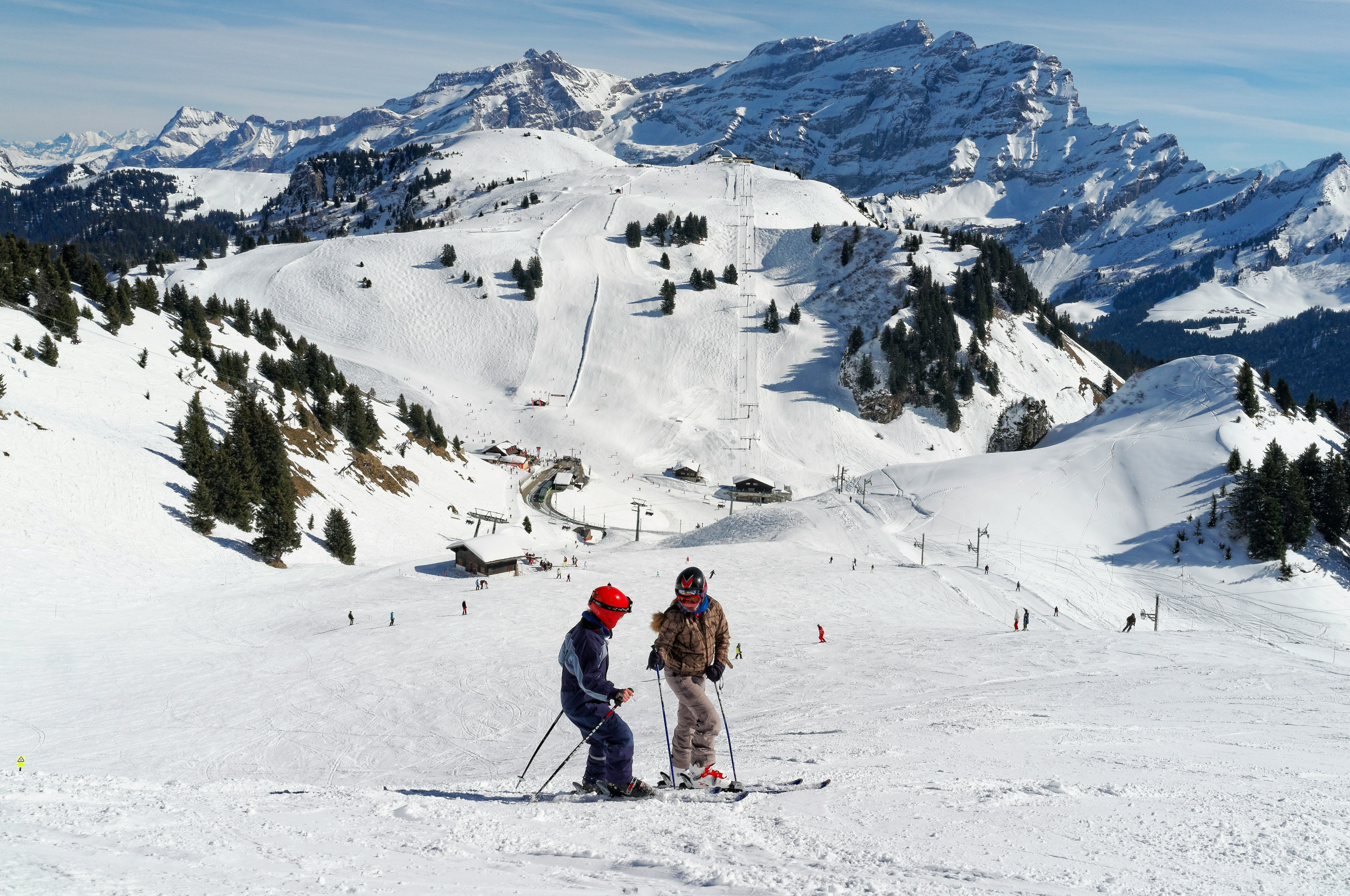 Lyžiar na zasneženom alpskom svahu s výhľadom na horské štíty a slnečnú oblohu